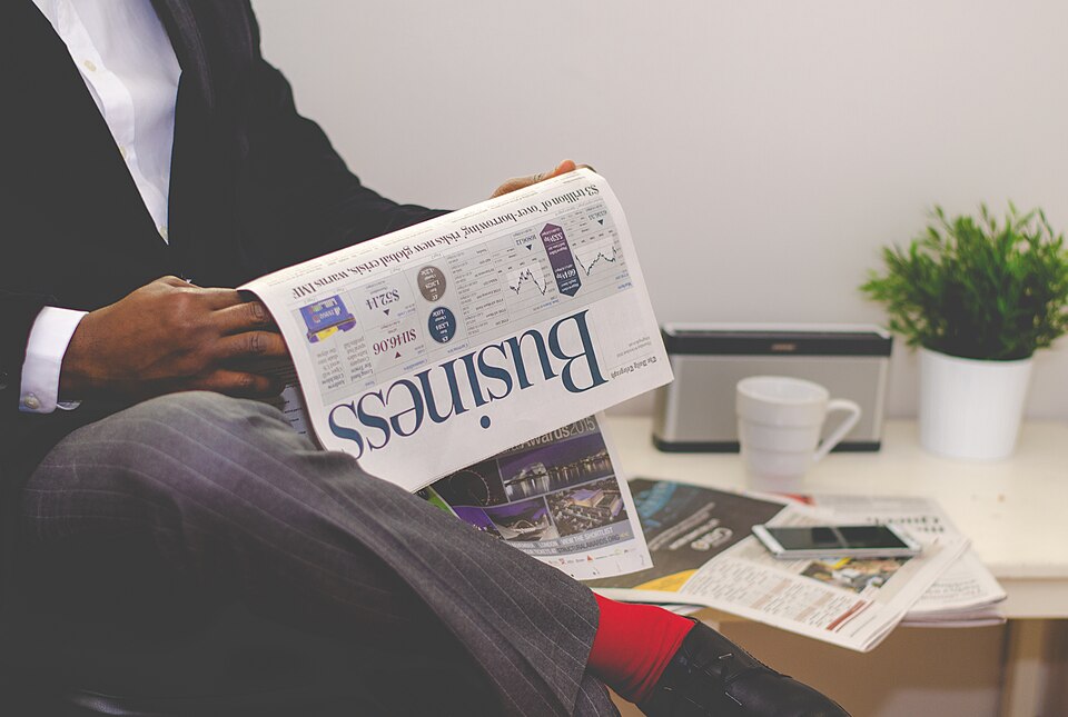 Jornal impresso aberto sobre a mesa, com outros exemplares ao lado