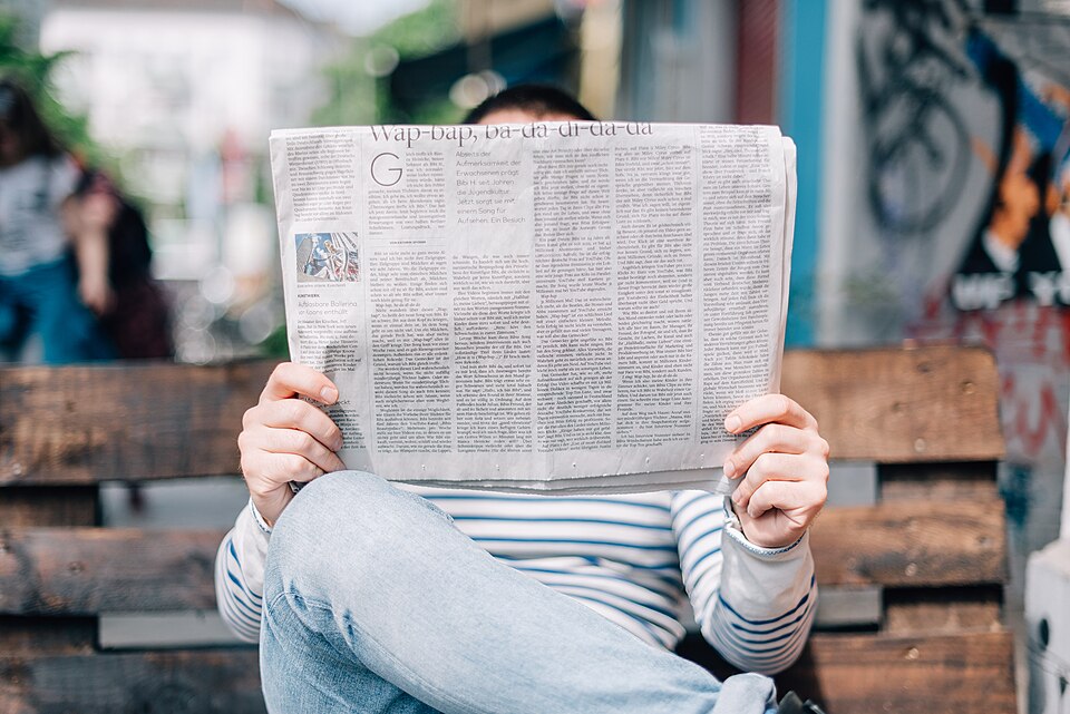 Pessoa lendo um jornal impresso ao ar livre